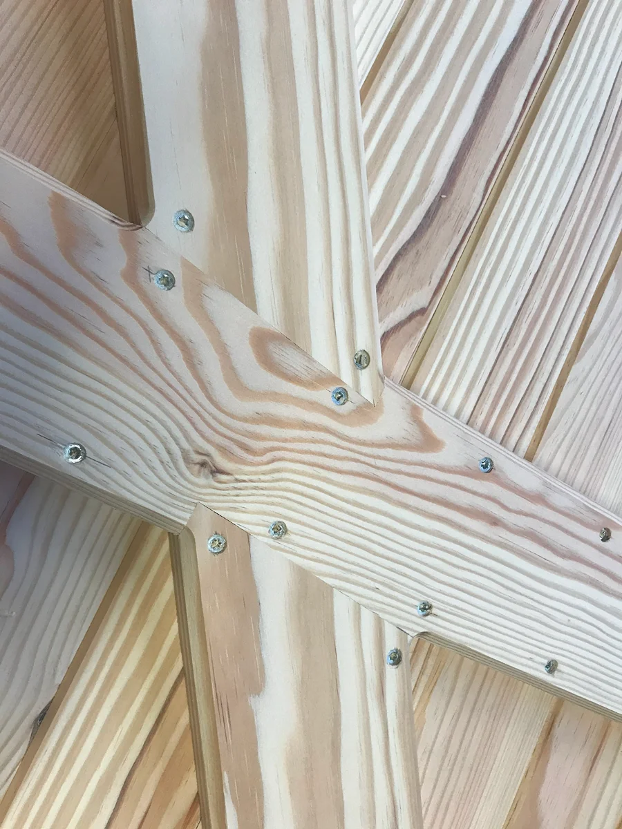 Croisement écharpe et traverse épaulée sur un volet en pin brut